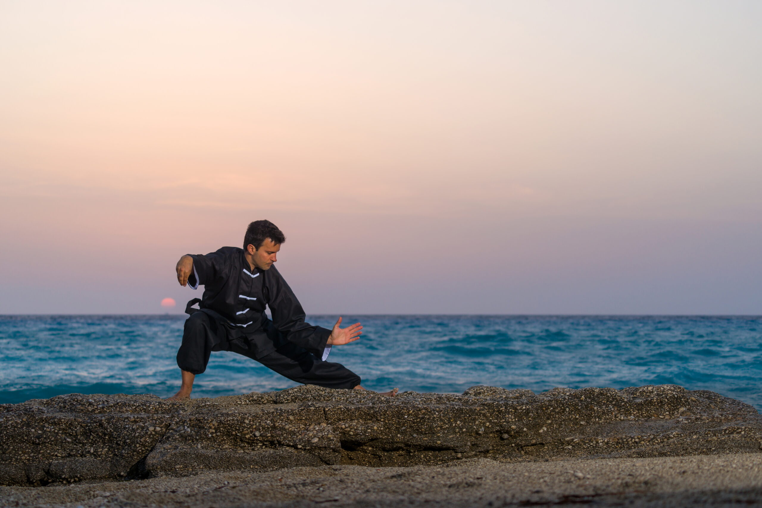 Man doing Kung Fu on beach with sunset - learn kung fu online