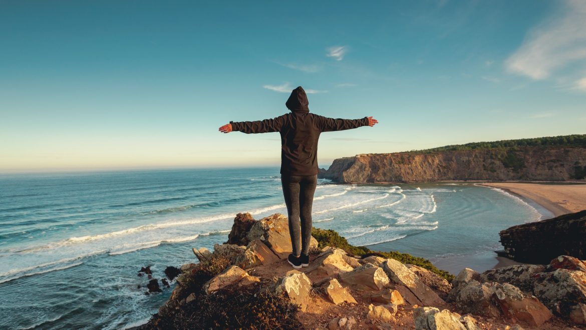 Freedom standing on rocks facing sea