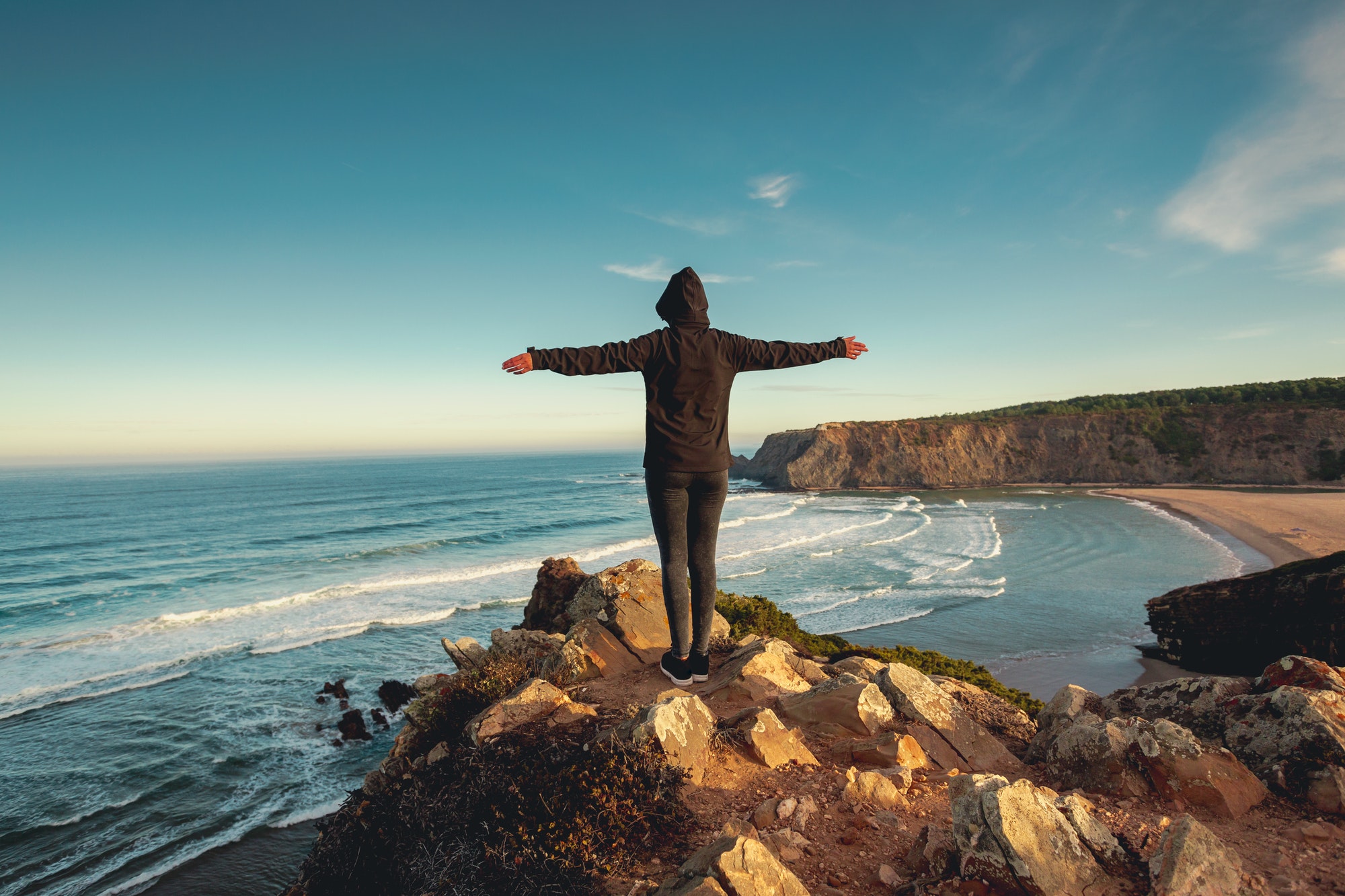 Freedom standing on rocks facing sea